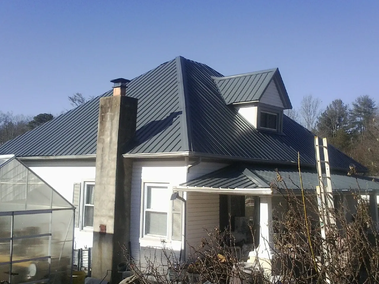 Dark blue standing seam metal roof on a white farmhouse with dormer — Slate & Tile Roof Repair by Roofing Brothers in Willowbrook