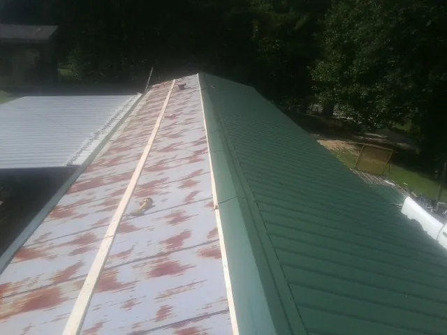 Old rusted panels beside newly installed green metal roofing — Wind Damage Roof Repair by Roofing Brothers in Willowbrook