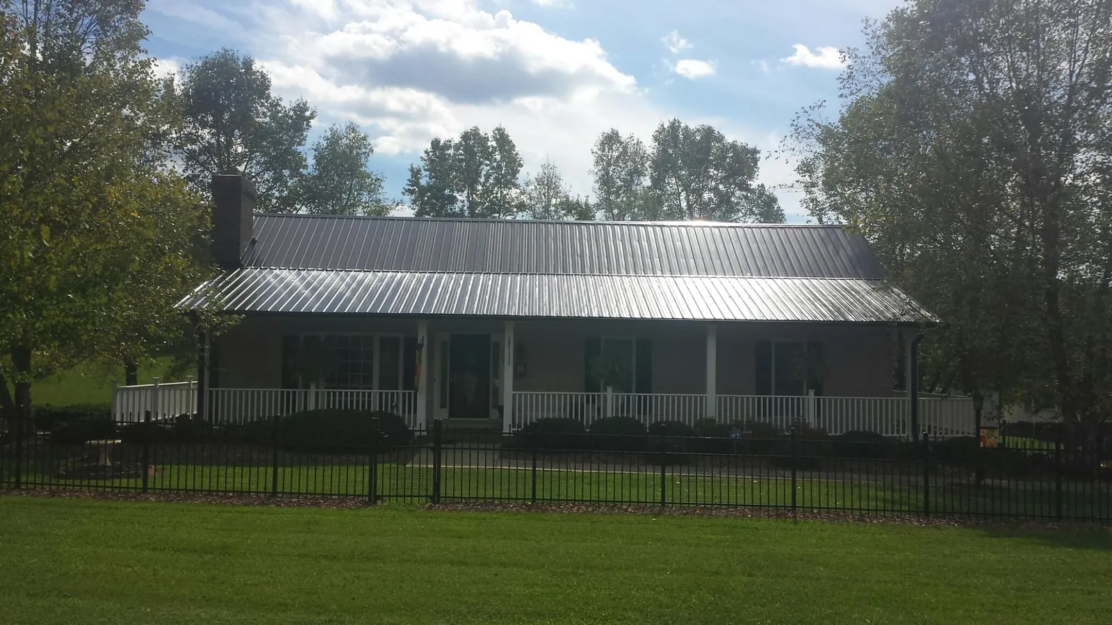 Gray metal roof on a brick ranch with a full width front porch — Gutter Guard Installation work by our crew in Willowbrook