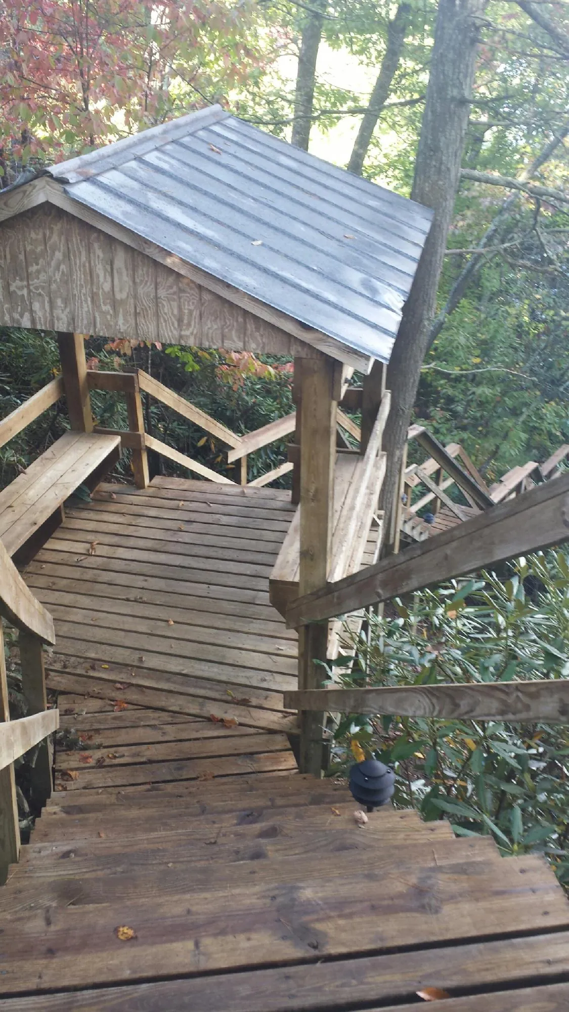 Metal roofed shelter over wooden steps on a wooded walkway — Skylight Repair & Installation work by our crew in Willowbrook